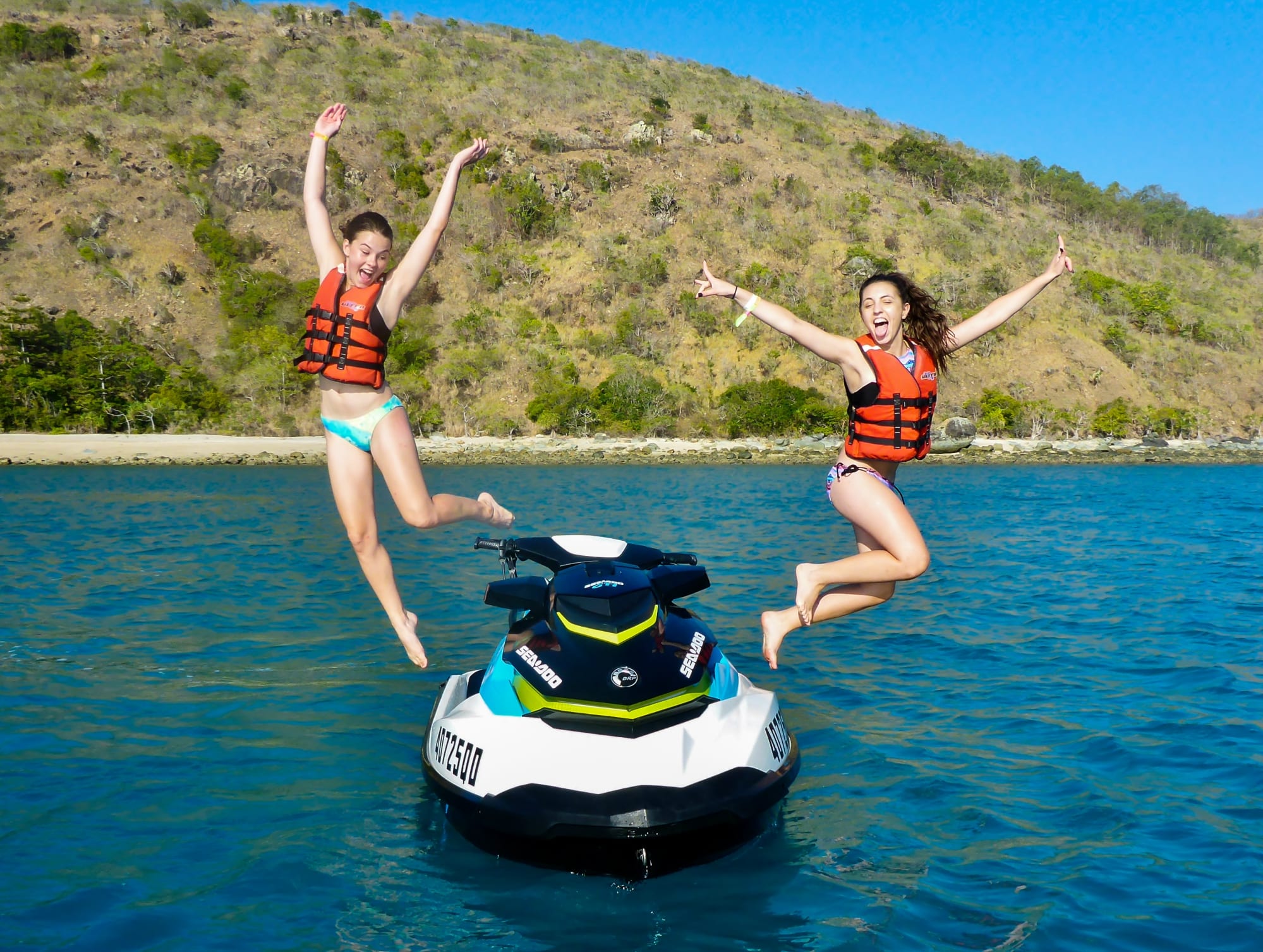 Two girls jumping off their jet ski into the ocean near Airlie Beach