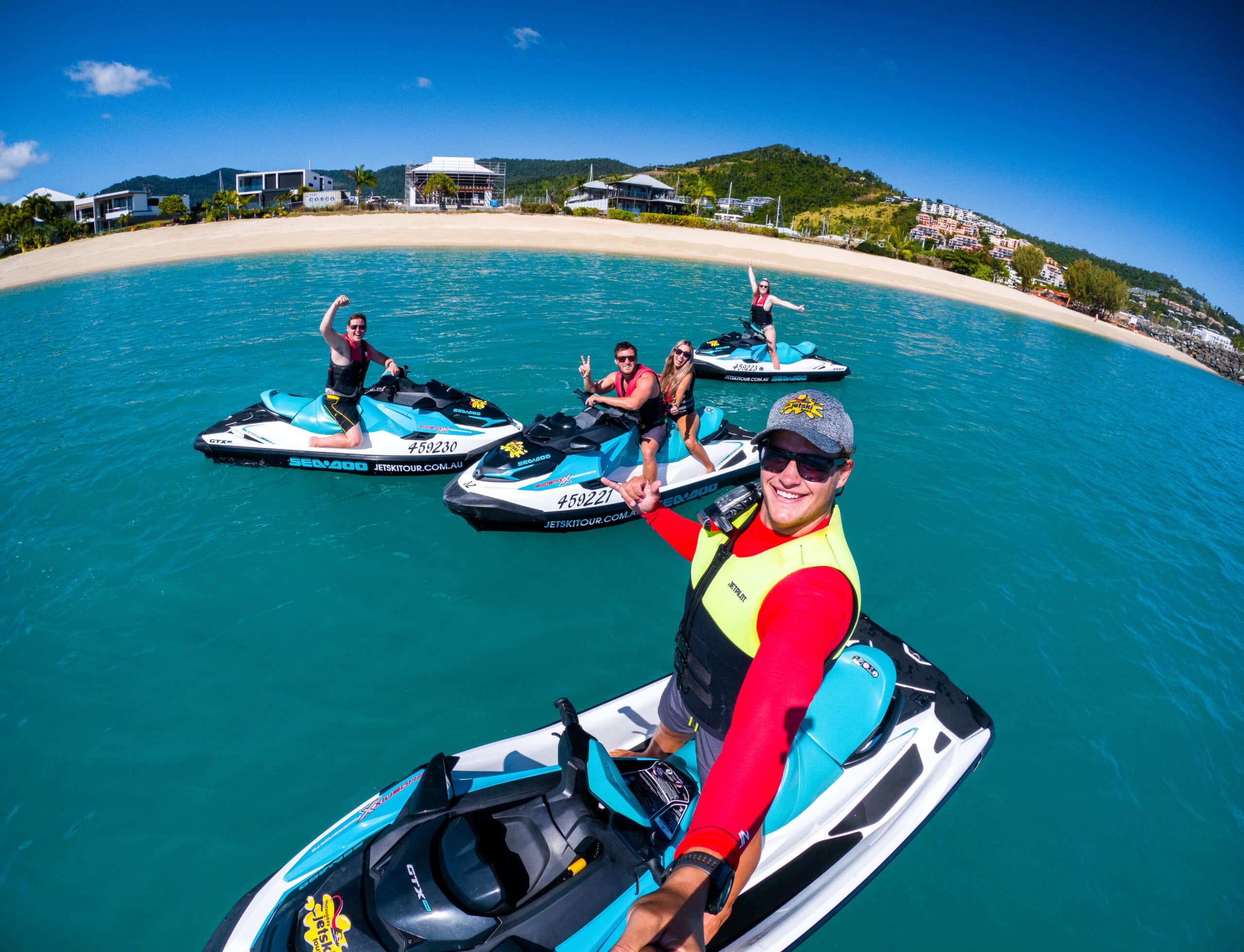 A jet ski tour group on their skis by the beach.