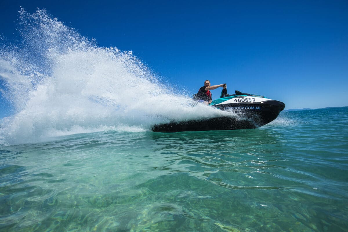 A man creating a great spray behind his jet ski.